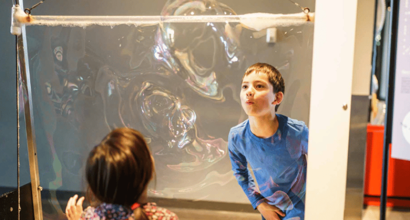 Un Des enfants soufflent pour faire des bulles de savon à l’exposition EXPLORE du centre des sciences de Montréal 