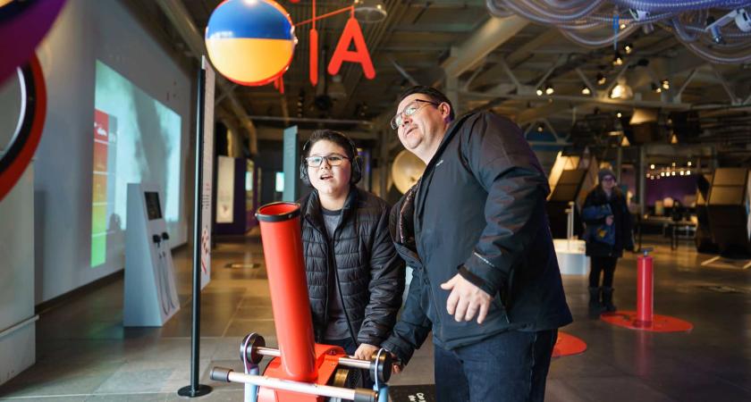 Père et son fils maintenant une balle grâce à une souffleuse.